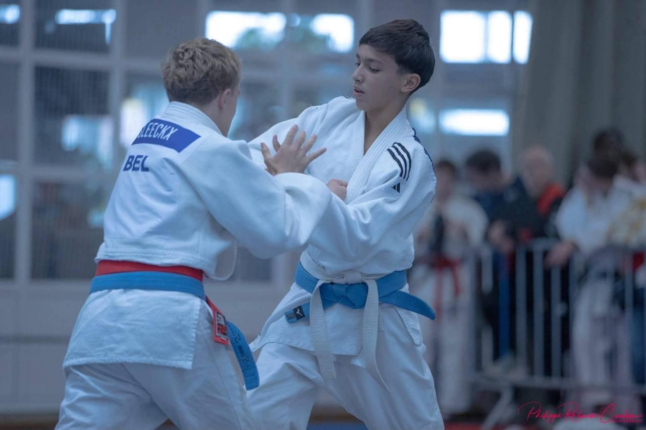Two young judoka in white judogi gripping each other's jackets during a match