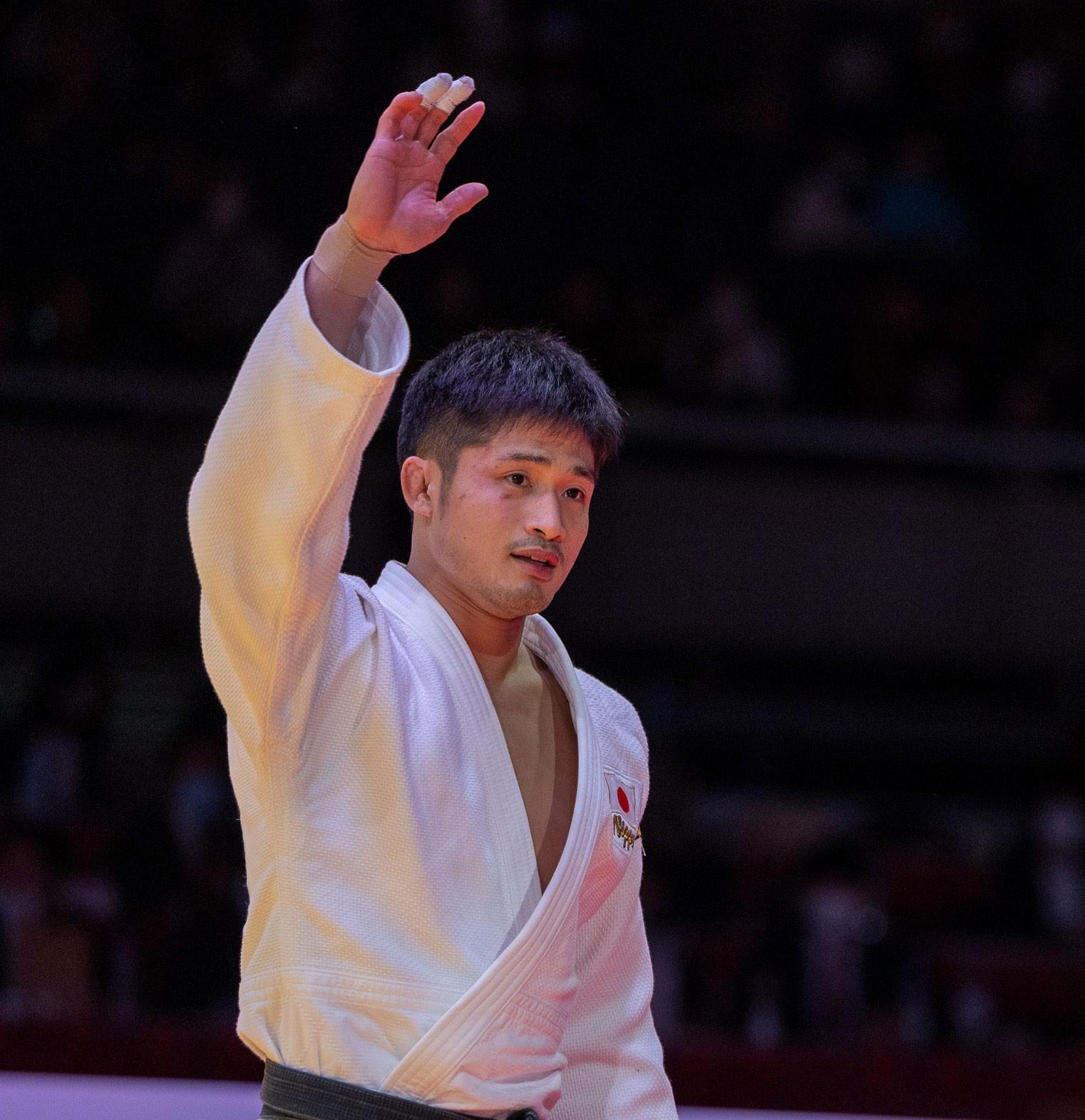 Coach guiding a young judoka through a throw on yellow tatami mats